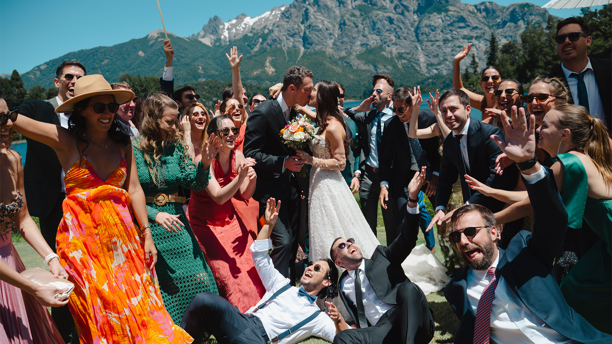 Los novios se besan rodeados de sus familiares y amigos que celebran felices su boda en uno de los lugares más hermosos, Bariloche, Patagonia. Dupla Planners lo hizo posible.