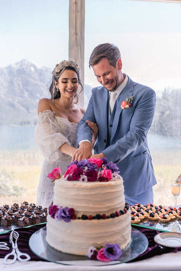 novios elegantes sonrien felices cortando su hermosa torta boda decorada con flores destination wedding bariloche patagonia argentina dupla planners